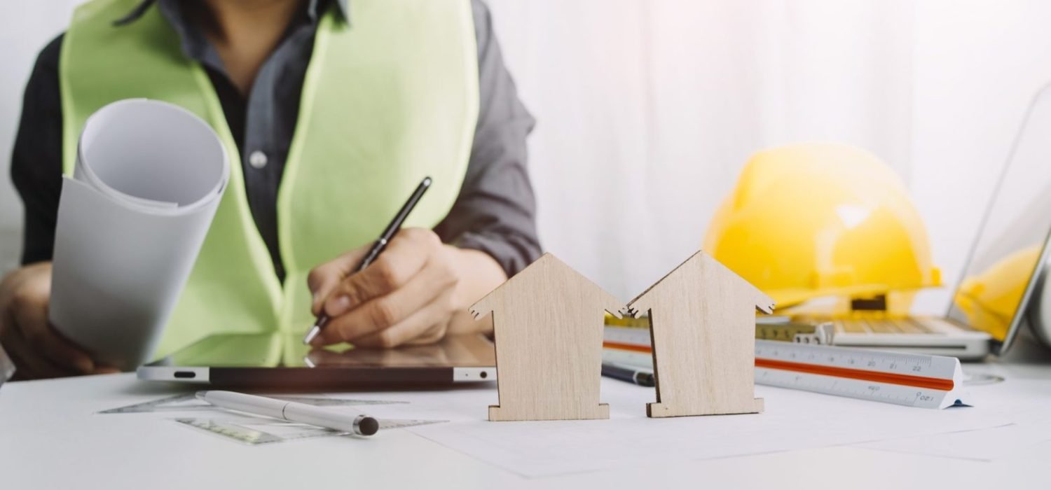 Two colleagues discussing data working and tablet, laptop with on on architectural project at construction site at desk in office
